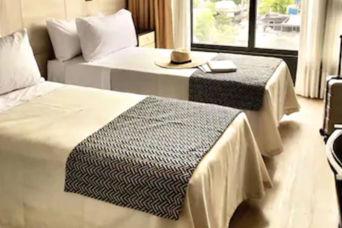 Une chambre d’hôtel avec deux lits, un bureau, une lampe et une vue sur la ville.