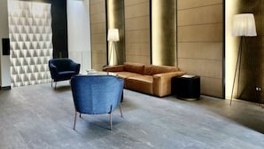 A modern lobby with a blue chair, a brown sofa, and a lamp. - RQ Express Costanera (Santiago)