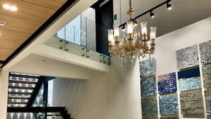 A spacious interior with a staircase leading to a balcony, a chandelier, and abstract wall art. - RQ Express Costanera (Santiago)