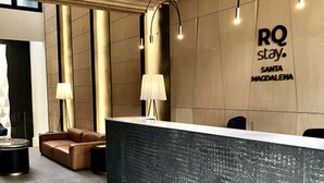 A reception desk with a modern design, featuring a wooden ceiling and a wall with the text "RQ stay. Santa Magdalena". - RQ Express Costanera (Santiago)