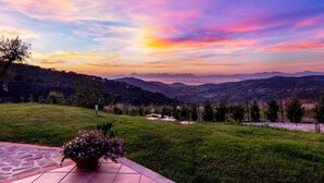 Una vista panorámica de una zona cubierta de césped con una maceta, con vistas a un valle y montañas lejanas, así como una masa de agua.