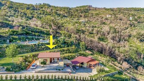 Propiedad en una ladera con una casa, piscina y jardín.