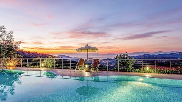 Una piscina con vistas al atardecer, una silla de descanso y una sombrilla.