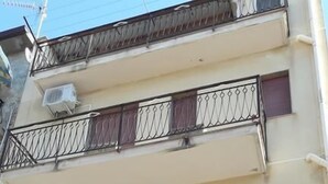 A multi-story building with balconies, air conditioning units, and a door with a number plaque. - B&B Maia House (Santo Stefano di Camastra)