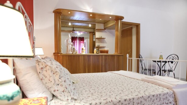 A bedroom with a bed, a wooden dresser, a mirror, and a dining area with chairs and a table. - B&B Maia House (Santo Stefano di Camastra)