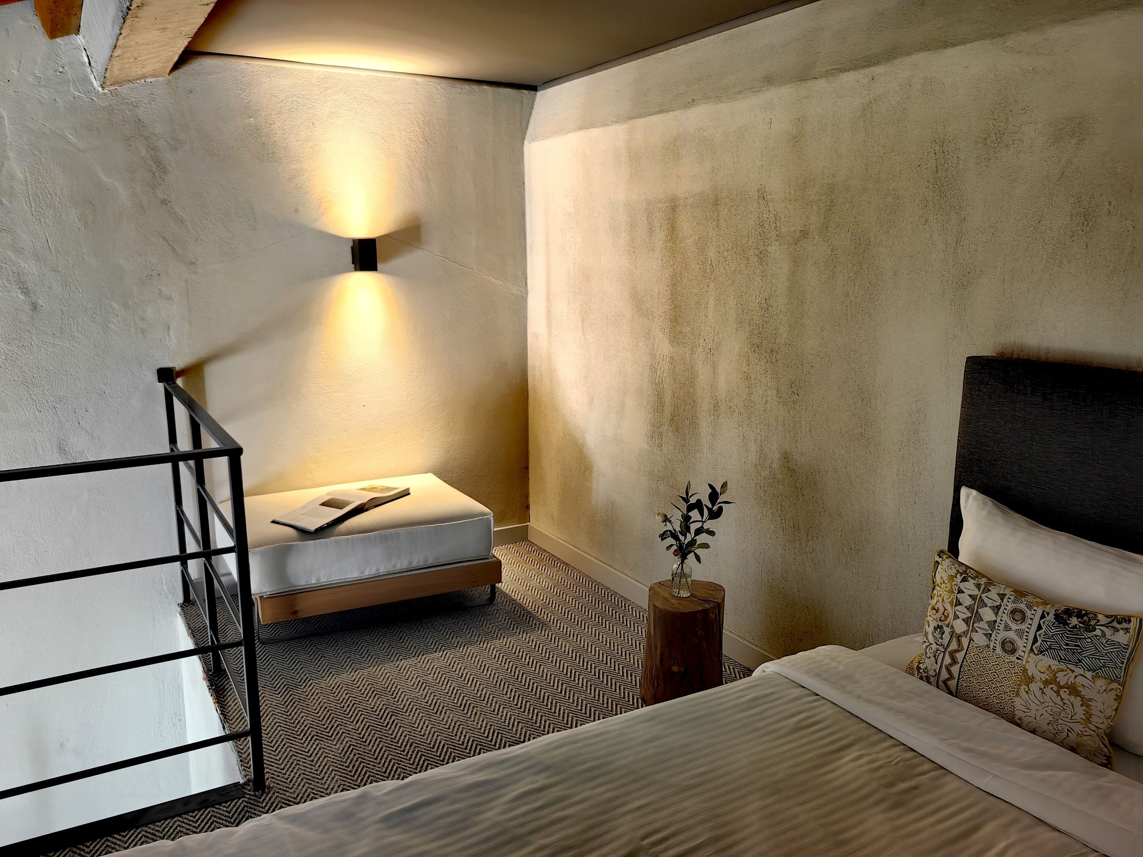 A modern bedroom with a bed, a bedside table, a nightstand, and a wall-mounted light fixture.