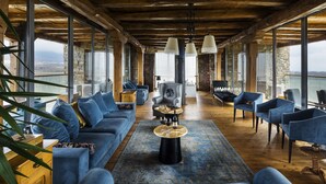 A spacious living room with a large sofa set, a coffee table, and multiple chairs. The room features large windows offering a view of the outdoors. - Maison & Chateau Copsa (Karlovo)