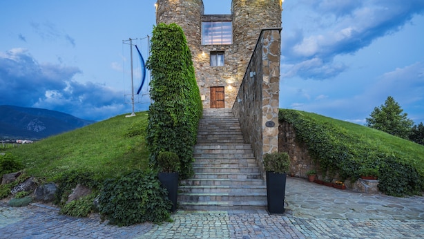 A stone staircase leading to a castle-like building with a wooden door, surrounded by lush greenery and a cobblestone path. - Maison & Chateau Copsa (Karlovo)