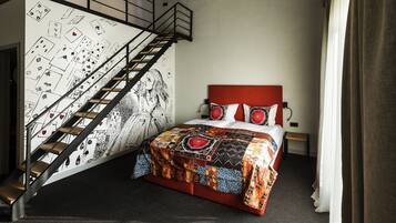 Un dormitorio con cama, una escalera y una pared decorada con ilustraciones de juegos de cartas.