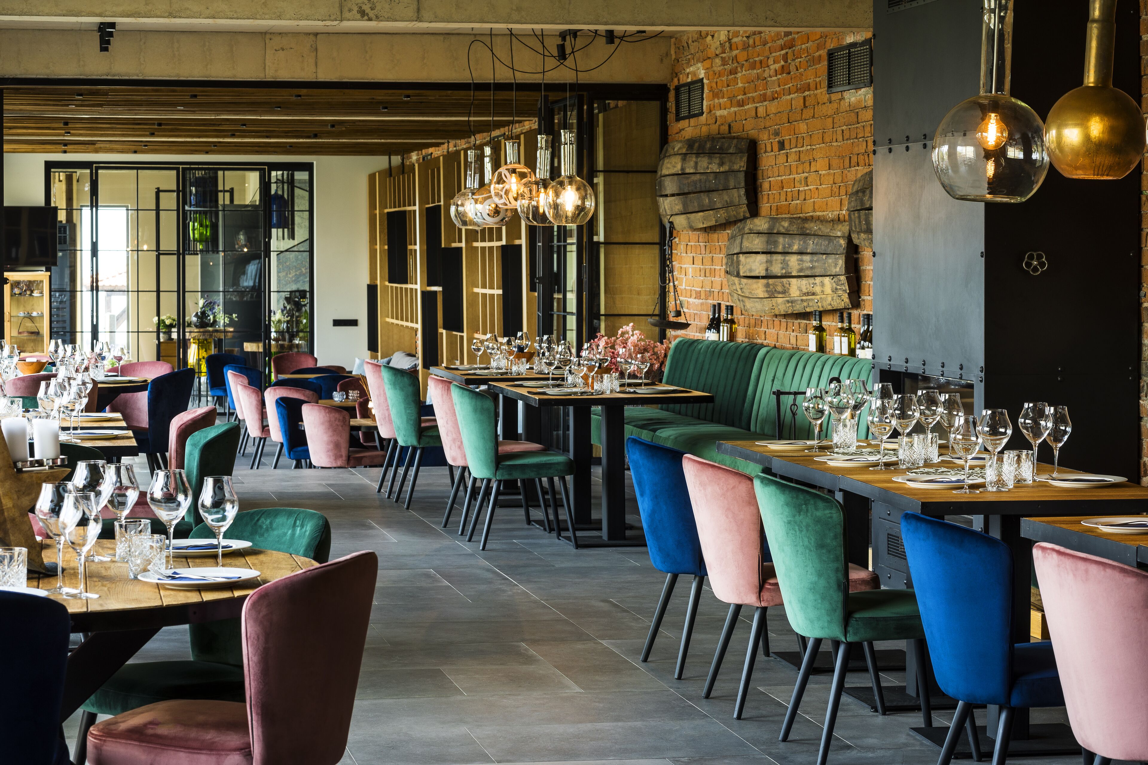 A restaurant with multiple dining tables, colorful chairs, and hanging pendant lights.