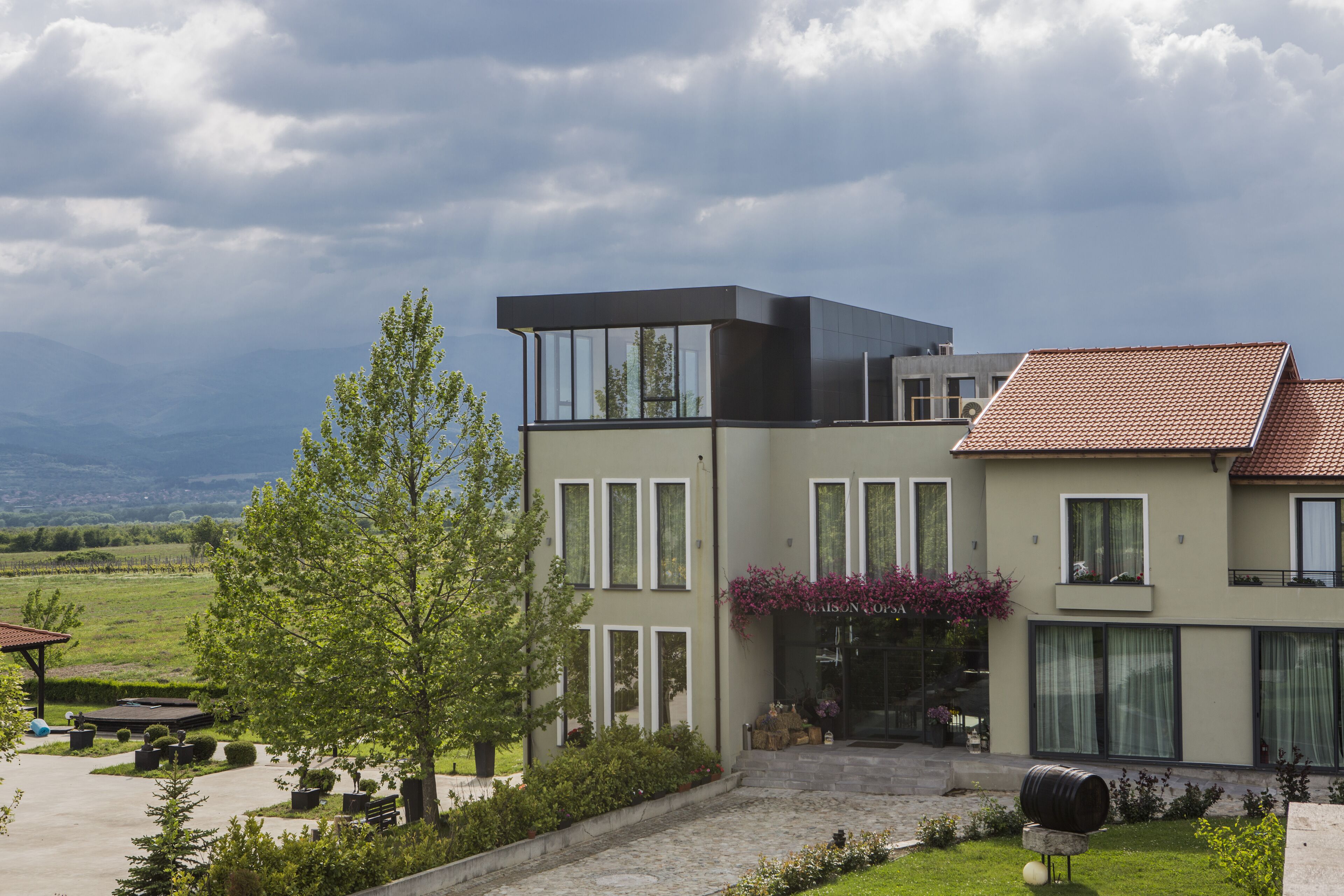 A modern two-story house with a large front porch, a covered outdoor seating area, and a well-maintained garden.