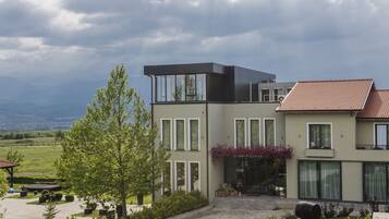 A modern two-story house with a large front porch, a covered outdoor seating area, and a well-maintained garden.