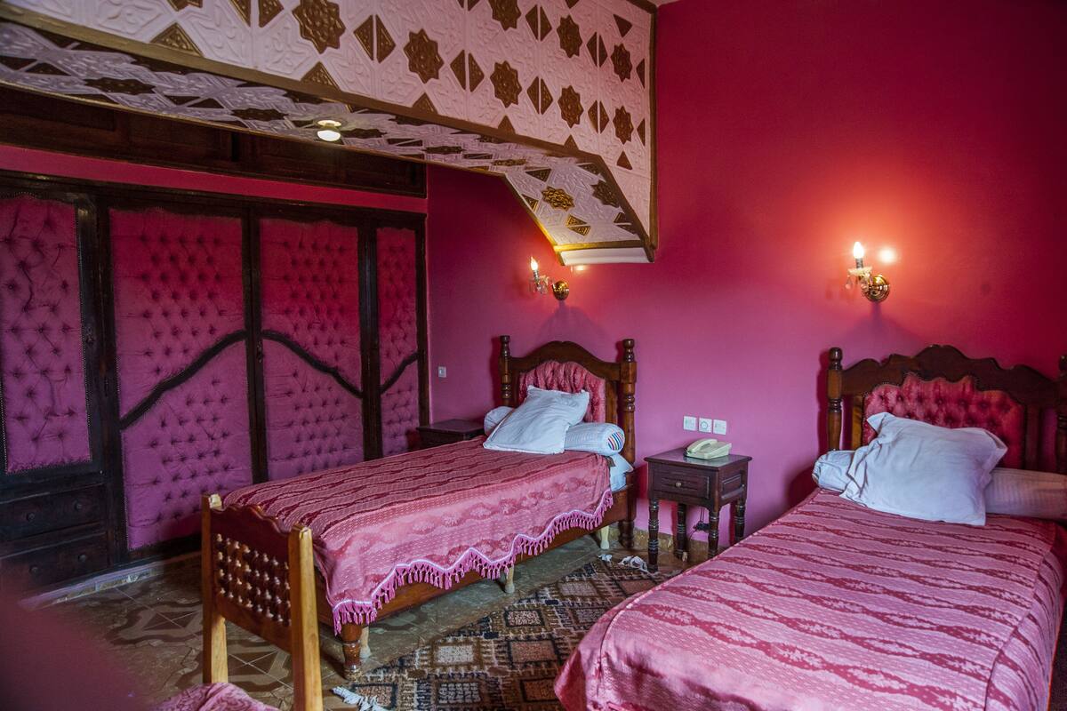 A room with two beds, a patterned floor, and a decorative ceiling.