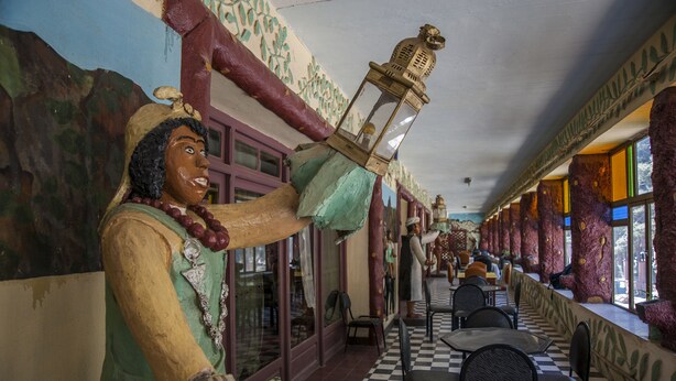 A restaurant with a checkered floor, wooden columns, and a statue of a person holding a lantern. - Hotel Todra Centre De Tinghir (Tinghir)