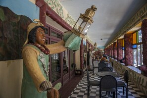 A restaurant with a checkered floor, wooden columns, and a statue of a person holding a lantern. - Hotel Todra Centre De Tinghir (Tinghir)