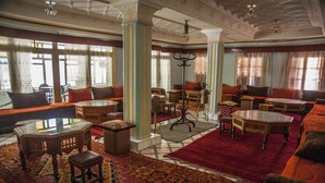 A spacious lobby with a mix of seating areas, including sofas and armchairs, a coffee table, and a patterned rug. - Hotel Todra Centre De Tinghir (Tinghir)