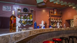 A bar area with a marble counter, shelves of bottles, and three red stools. - Hotel Todra Centre De Tinghir (Tinghir)