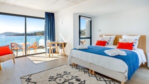Een moderne hotelkamer met een groot bed, een bureau en uitzicht op zee.
