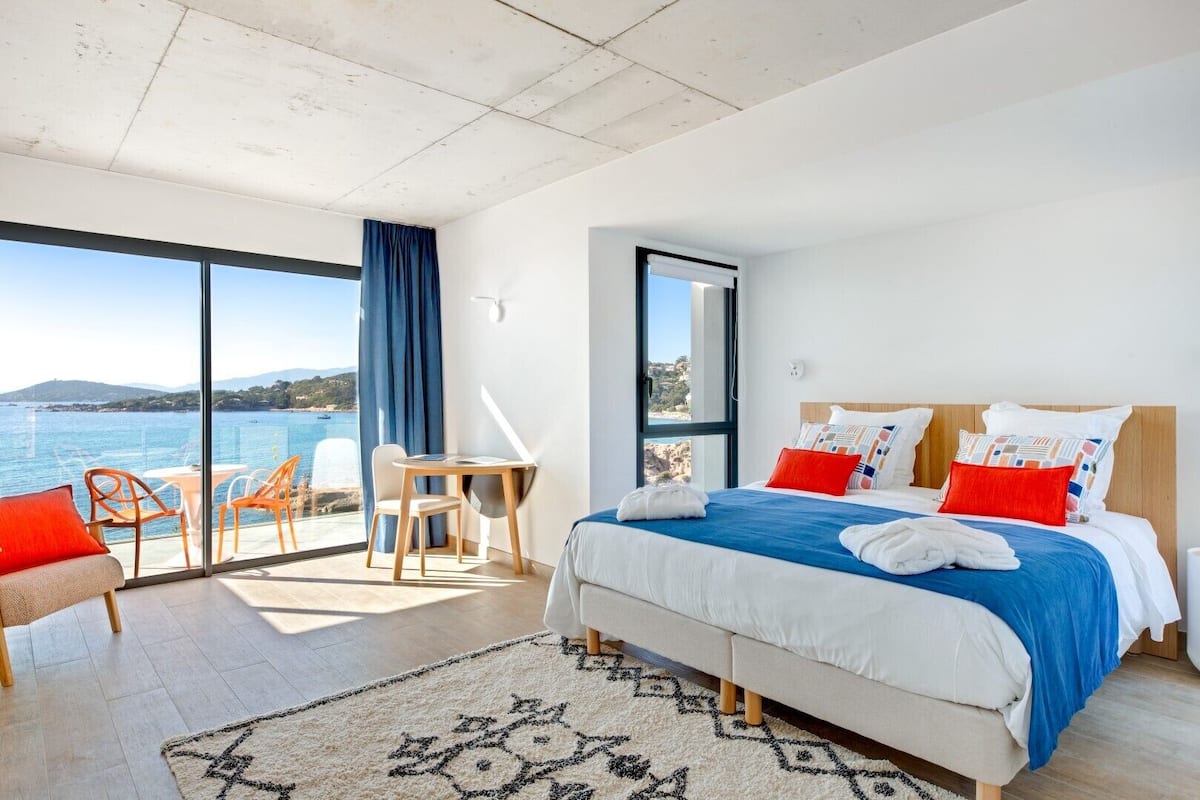 Ein modernes Hotelzimmer mit einem großen Bett, einem Schreibtisch und Blick auf das Meer.