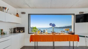 Een moderne keuken met een groot raam met uitzicht op een schilderachtig kustlandschap.