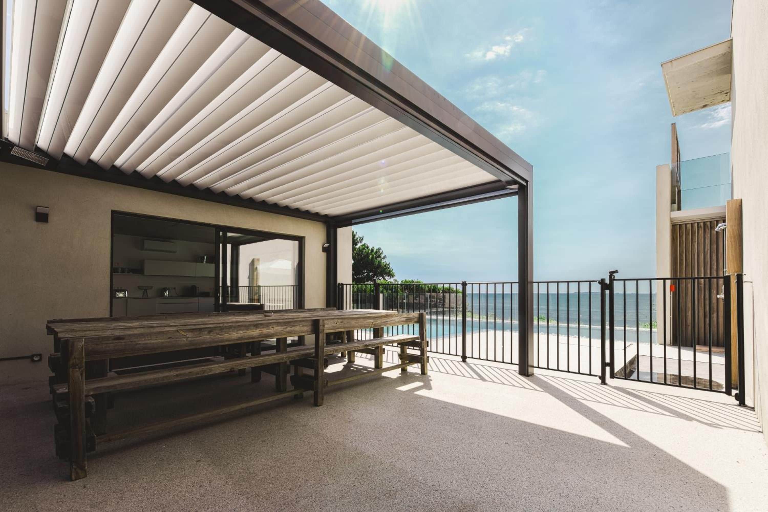 A covered outdoor seating area with a view of the sea.