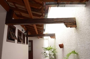 A wooden ceiling structure with exposed beams, a white textured wall, and a small potted plant.