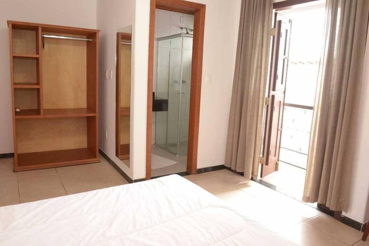 A bedroom with a bed, a wooden wardrobe, a glass shower, and a sliding glass door to the outside.