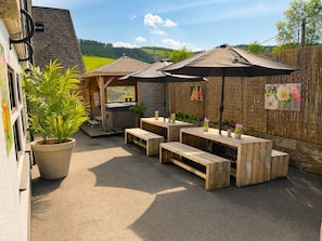 Une terrasse extérieure avec des tables et des bancs en bois, un jacuzzi et une clôture en bois.