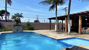 Una piscina al aire libre, sombrillas, sillones reclinables de piscina