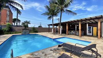 Una piscina al aire libre, sombrillas, sillones reclinables de piscina