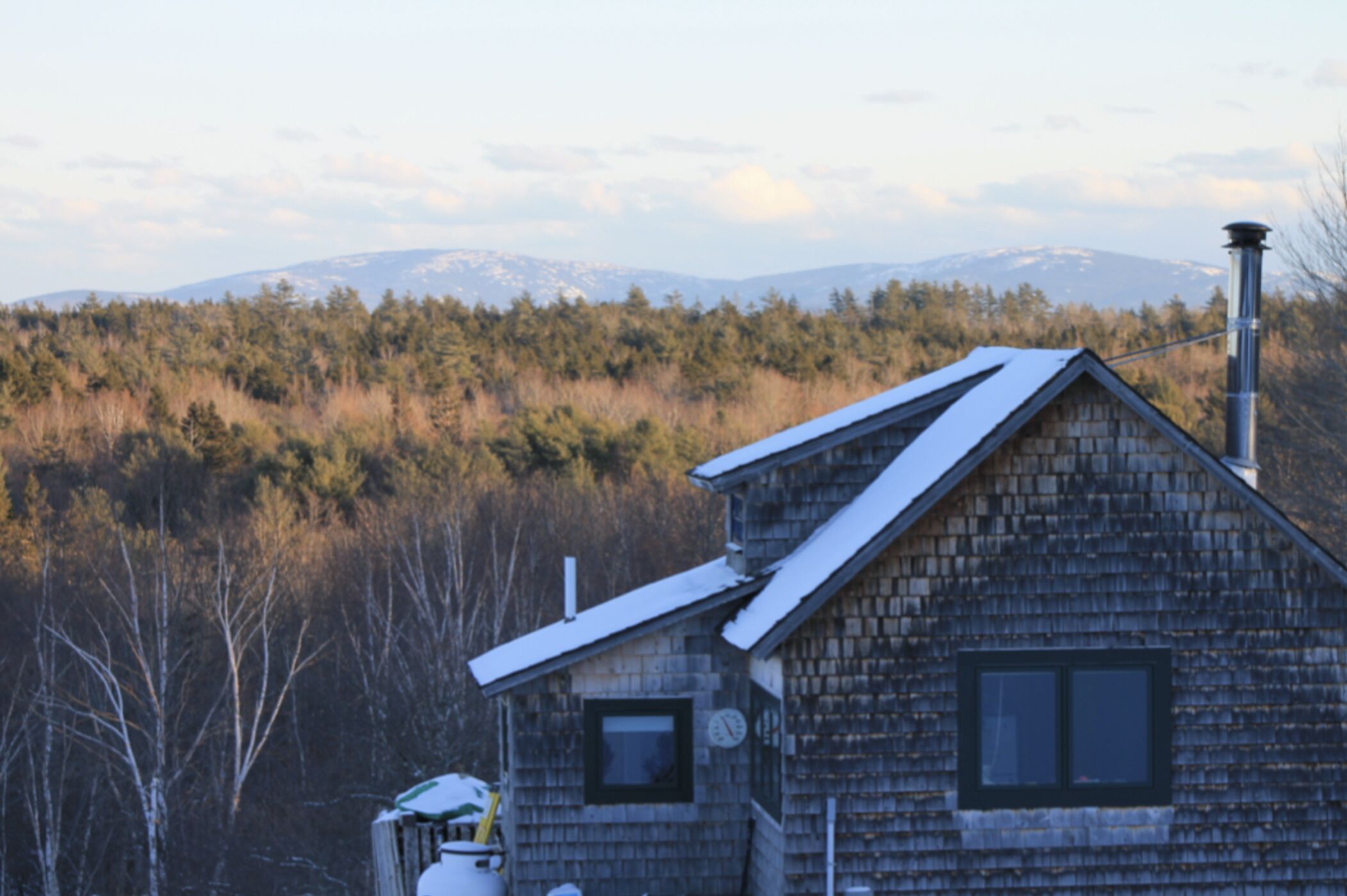 Une cabane rustique avec un toit en pente, une cheminée et une fenêtre.