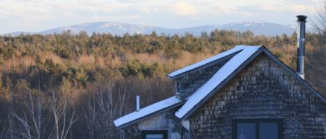Une cabane rustique avec un toit en pente, une cheminée et une fenêtre.