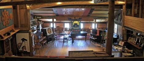 Un interior rústico con vigas de madera, un piano de cola y diversas obras de arte.
