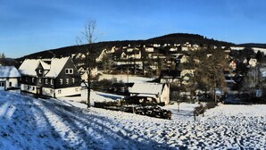 A snow-covered landscape with a traditional European village, including houses with sloped roofs and a clear sky. - Very quiet holiday home in the Rothaar Mountains (Vormwald)