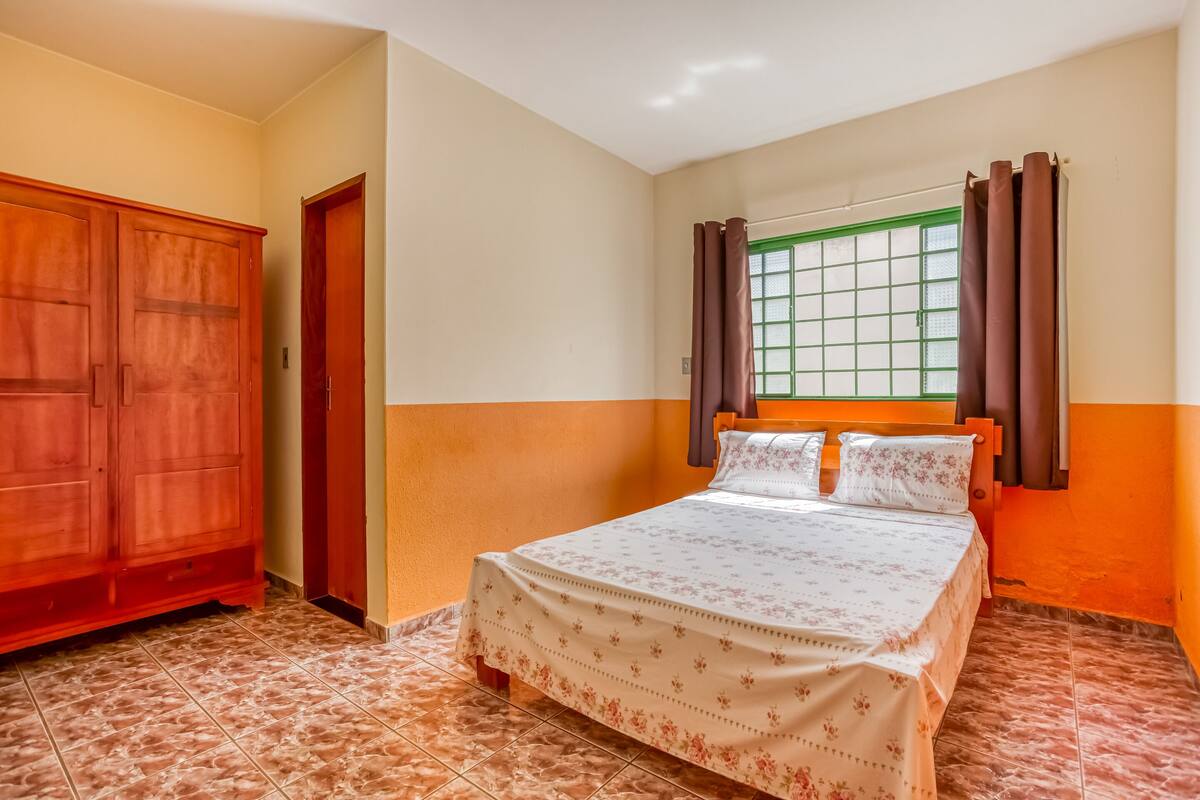 A bedroom with a bed, a wardrobe, and a window with curtains.