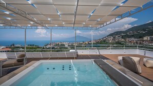 Zona de piscina en la azotea con vistas a un pueblo costero y montañas.
