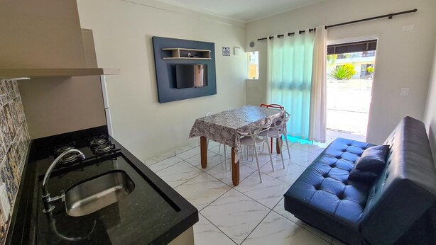 A compact living space with a kitchenette, a dining table, and a sofa. - Residencial Miragem Bombinhas Duo (Bombinhas)
