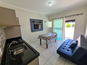A compact living space with a kitchenette, a dining table, and a sofa. - Residencial Miragem Bombinhas Duo (Bombinhas)