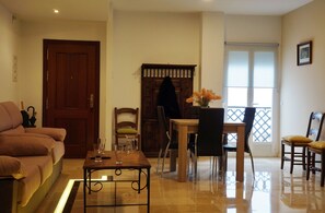 Un salon comprenant un canapé, une table basse, une table à manger avec des chaises, un meuble en bois et une fenêtre donnant sur un beau paysage.