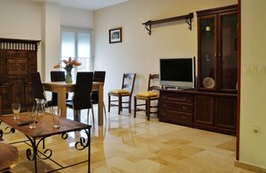 Un espace repas comprenant une table en bois, des chaises et un téléviseur.