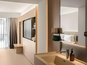 A modern hotel bathroom with a large mirror, a bathtub, and a vanity with a sink.