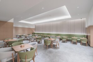 A modern restaurant with a high ceiling, recessed lighting, and a mix of green and white chairs and tables. - Ji Hotel Shanghai Hongqiao Wuzhong Road (Shanghai)