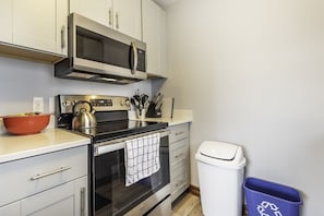 Una cocina moderna con electrodomésticos de acero inoxidable, microondas y hervidor en la estufa.