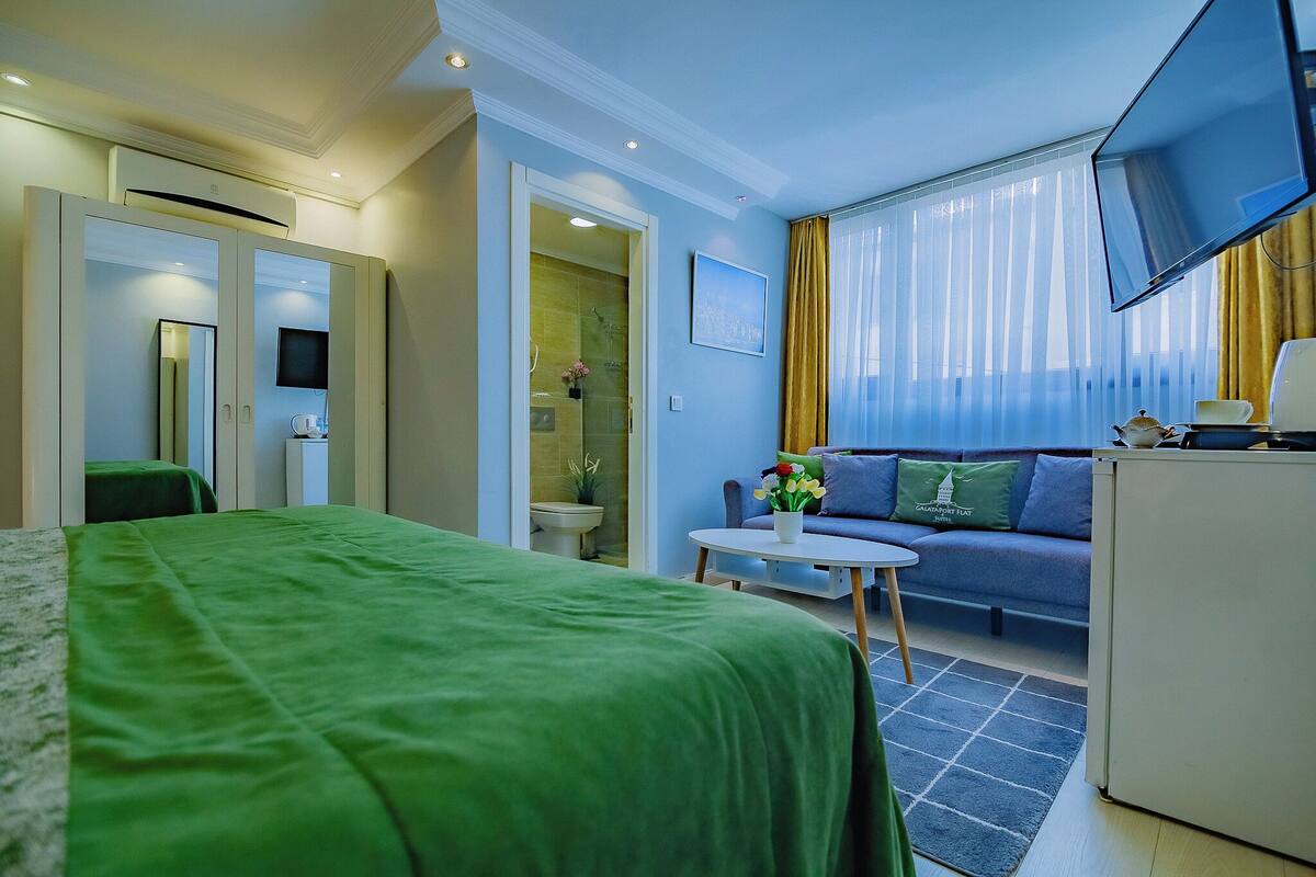 A hotel room with a bed, a sofa, a TV, and a desk.