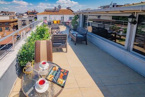 A rooftop terrace with a table set for two, a teapot, and a menu. - Galata Nil Suite (Istanbul)