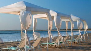 Ein Strand mit weißen Sonnensegeln und Liegestühlen.