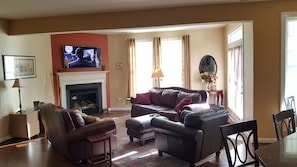 A living room with a fireplace, leather furniture, and a television on the wall.