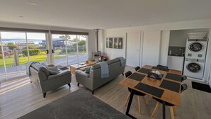 Ein modernes Wohnzimmer mit einer Couch, einem Esstisch und einer Küchenzeile inklusive Waschmaschine.