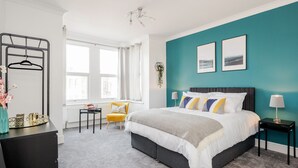 A bedroom with a bed, a desk, a chair, and a window.
