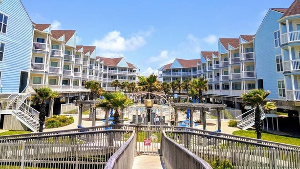 Ein Strandhotel mit mehrstöckigen Gebäuden, Balkonen und einem zentralen Gang.